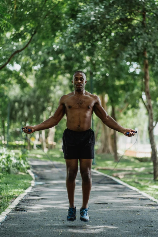 a man standing on a path in the middle of a park, happening, wearing a tank top and shorts, bouncing, man is with black skin, connectivity