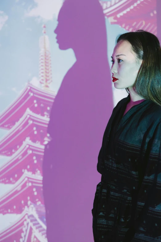 a woman standing in front of a projection of a pagoda, an album cover, unsplash, ukiyo-e, demna gvasalia, wearing black and purple robes, nishihara isao, ( ( theatrical ) )