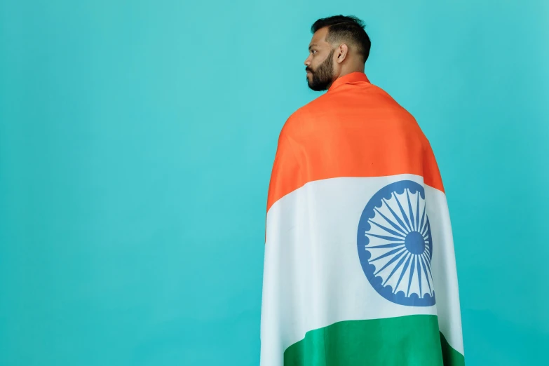 a man wearing an indian flag cape against a blue background, pexels contest winner, hurufiyya, middle of the page, plain background, teal orange, independence