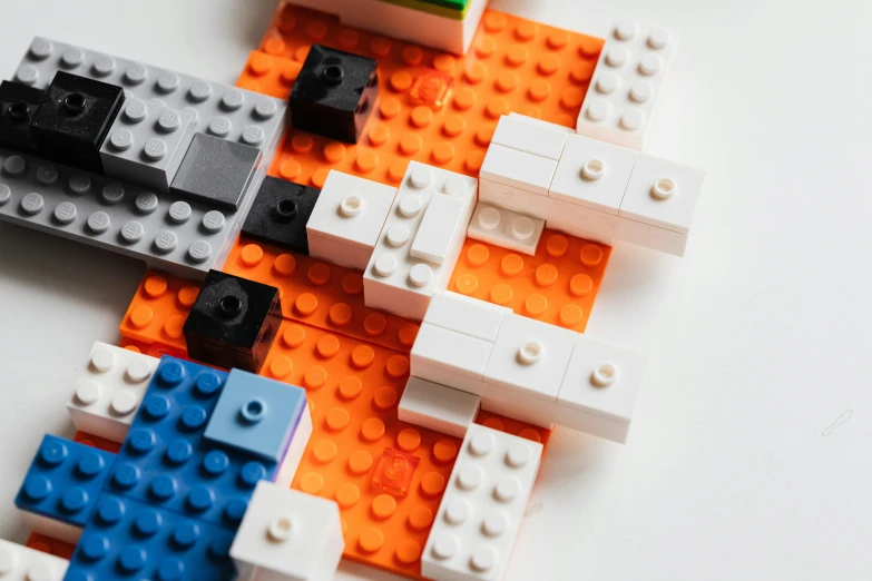 a group of legos sitting on top of a table, white and orange, orange and blue, detail shot, square shapes