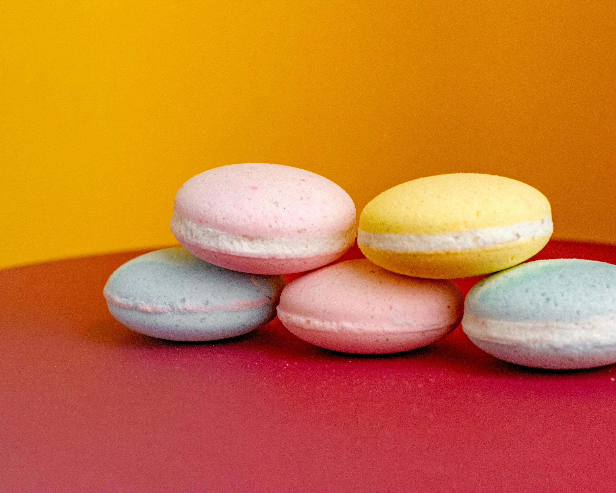 a pile of macarons sitting on top of a red table, trending on pexels, rainbow coloured rockets, sugar, thumbnail, 33mm photo