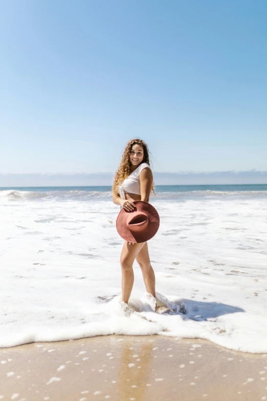 a woman standing on top of a beach next to the ocean, barrel chested, ceramics, instagram model, wavy