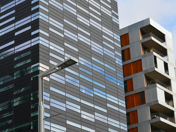 a couple of tall buildings next to each other, modernism, dark grey and orange colours, metal panels, commercial, commercial lighting