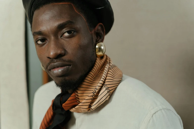 a close up of a person wearing a tie and a hat, inspired by Theo Constanté, trending on pexels, afrofuturism, wearing turtleneck, adut akech, earbuds jewelry, flowing golden scarf