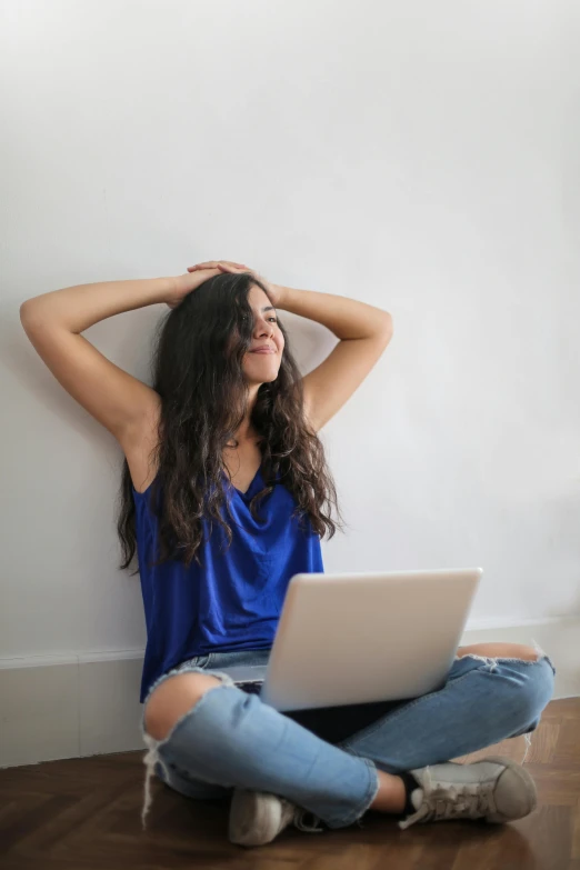 a woman sitting on the floor with her laptop, trending on pexels, renaissance, wearing a camisole, hands in her hair, wearing blue, leaning on the wall
