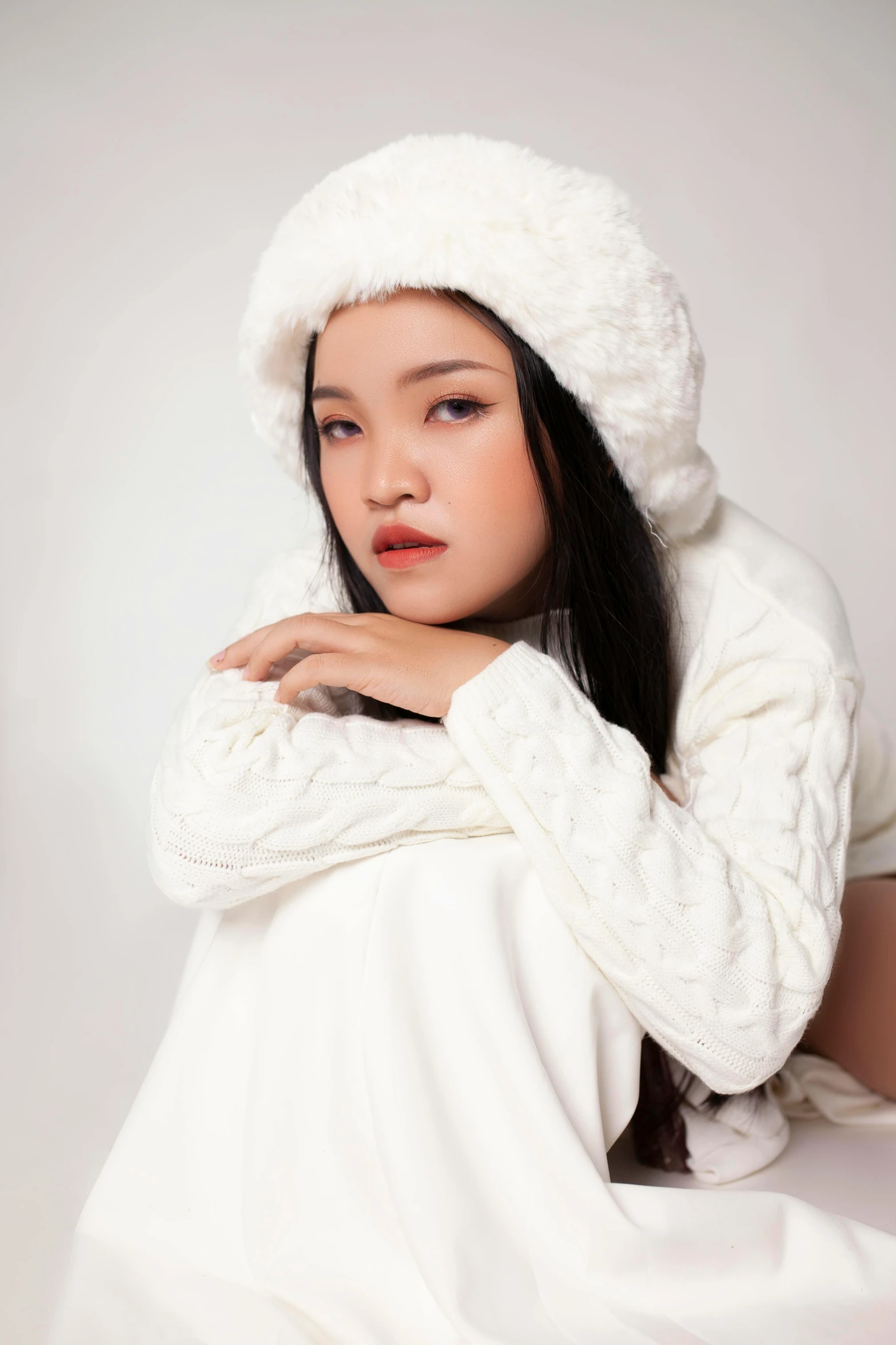 a woman in a white coat and hat laying on a bed, inspired by Huang Ji, trending on pexels, realism, very long snow colored hair, young asian girl, thoughtful pose, wearing beanie