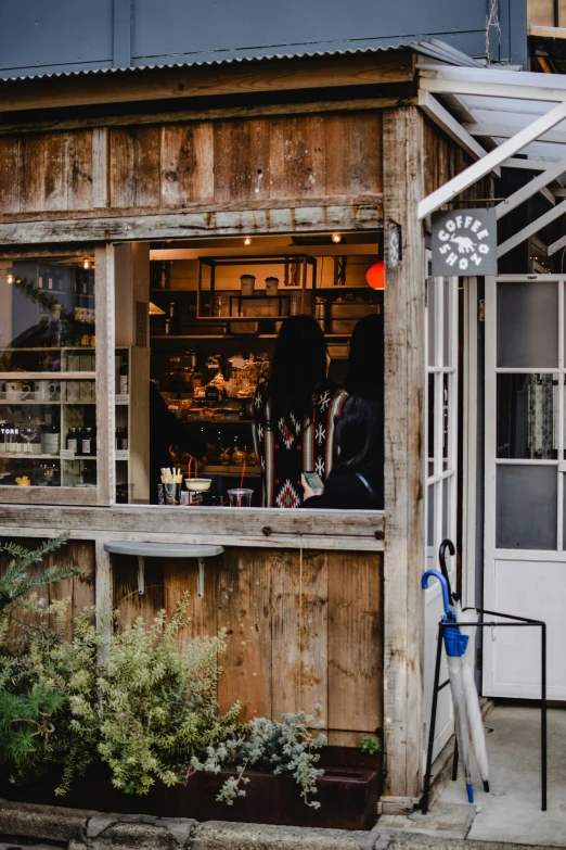 a small store sitting on the side of a road, trending on unsplash, renaissance, behind bar deck with bear mugs, hollister ranch, small library, looking from shoulder