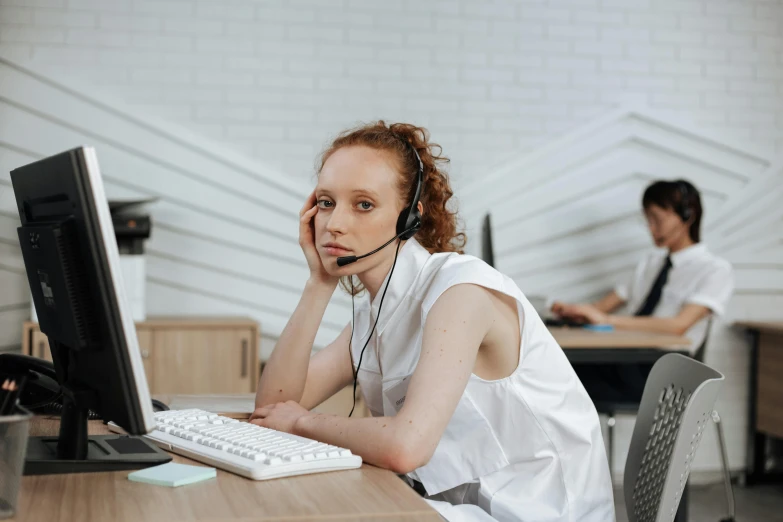 a woman sitting at a desk in front of a computer, trending on pexels, hurufiyya, in an call centre office, aussie, pale - skinned, broken down