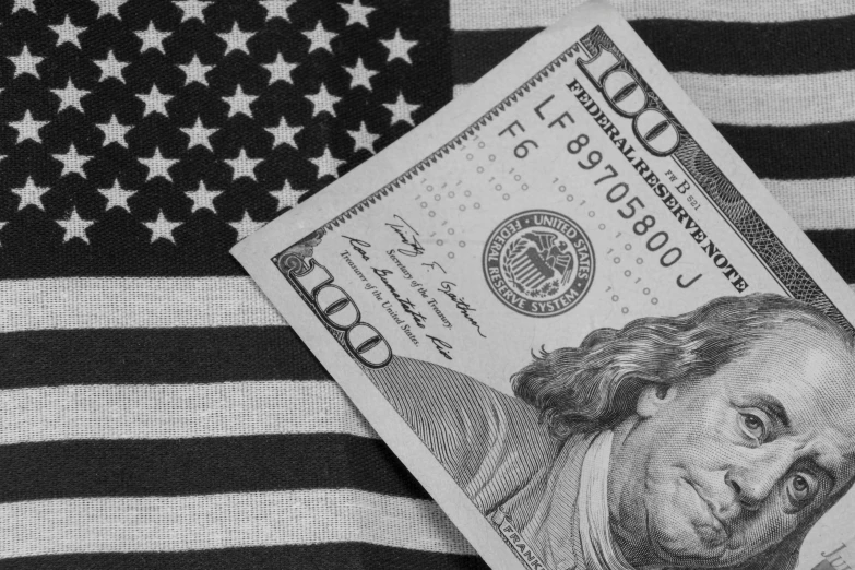 a hundred dollar bill laying on top of an american flag, a portrait, inspired by Benjamin Franklin, pexels, black & white, tiffany dover, a new