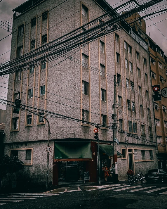 a tall building sitting on the side of a road, a colorized photo, inspired by Elsa Bleda, unsplash, quito school, electric cables, vintage footage on tokyo streets, location of a dark old house, gif