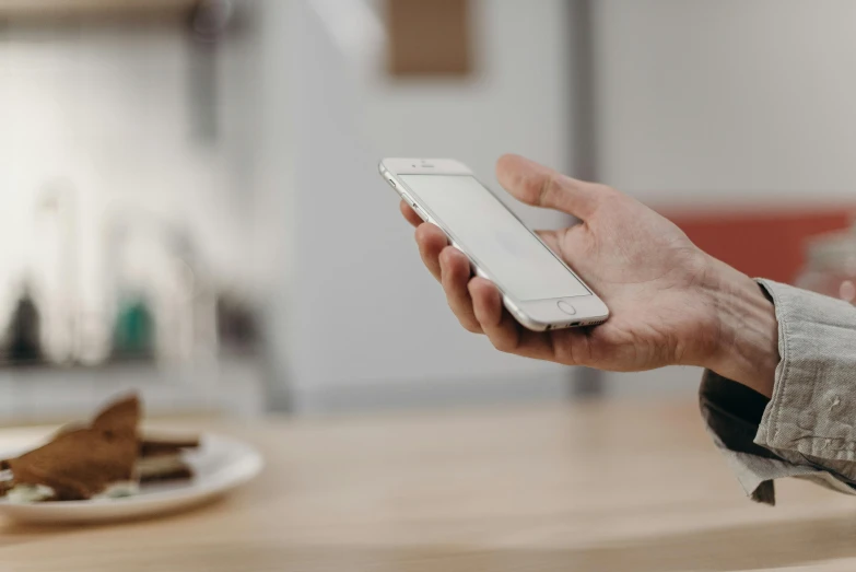 a close up of a person holding a cell phone, trending on pexels, over a dish and over a table, slightly turned to the right, full body image, brown