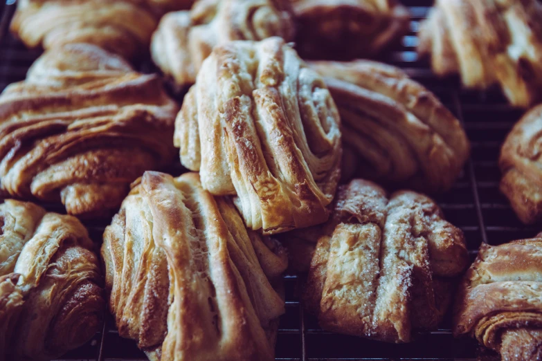 a bunch of croissants sitting on top of a cooling rack, a portrait, unsplash, baroque, intricate wrinkles, manuka, caramel, a wooden