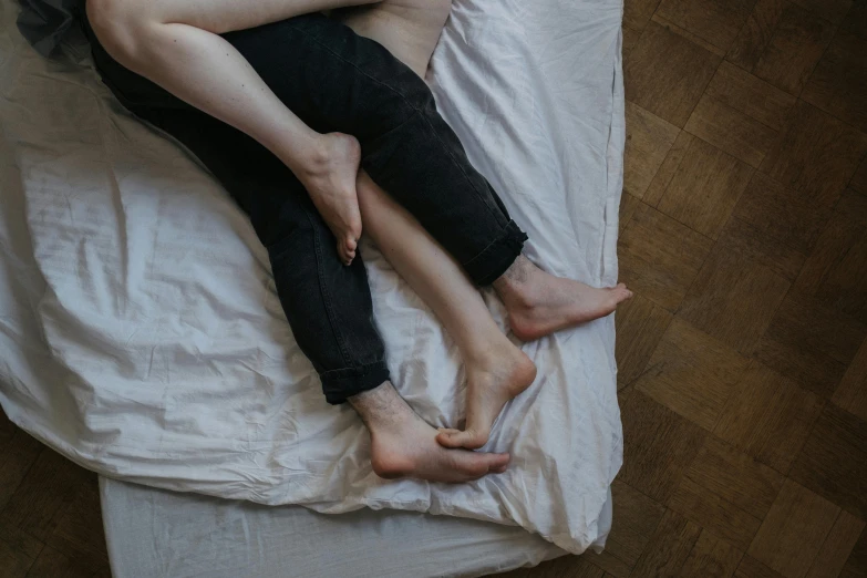 a man and a woman laying on top of a bed, trending on pexels, massurrealism, wearing only pants, holding each other, queer, full body human legs