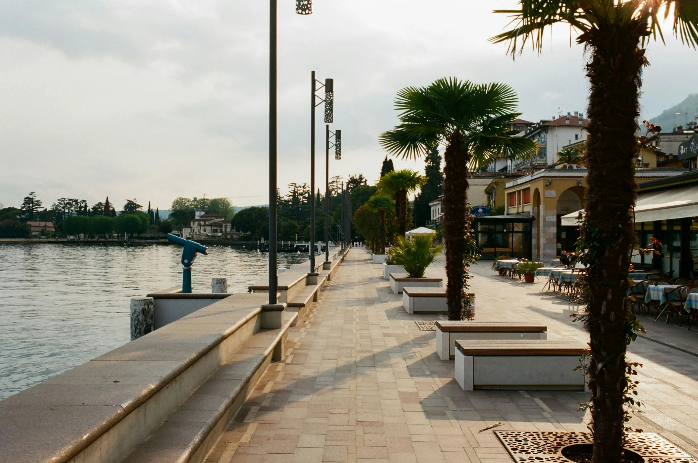 a row of benches sitting next to a body of water, inspired by Tommaso Redi, art nouveau, sidewalk, shops, lakeside, abbondio stazio