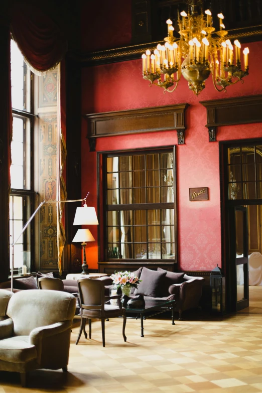 a living room filled with furniture and a chandelier, inspired by Ramon Pichot, unsplash, baroque, wine red trim, gentleman's club lounge, cairo, atrium