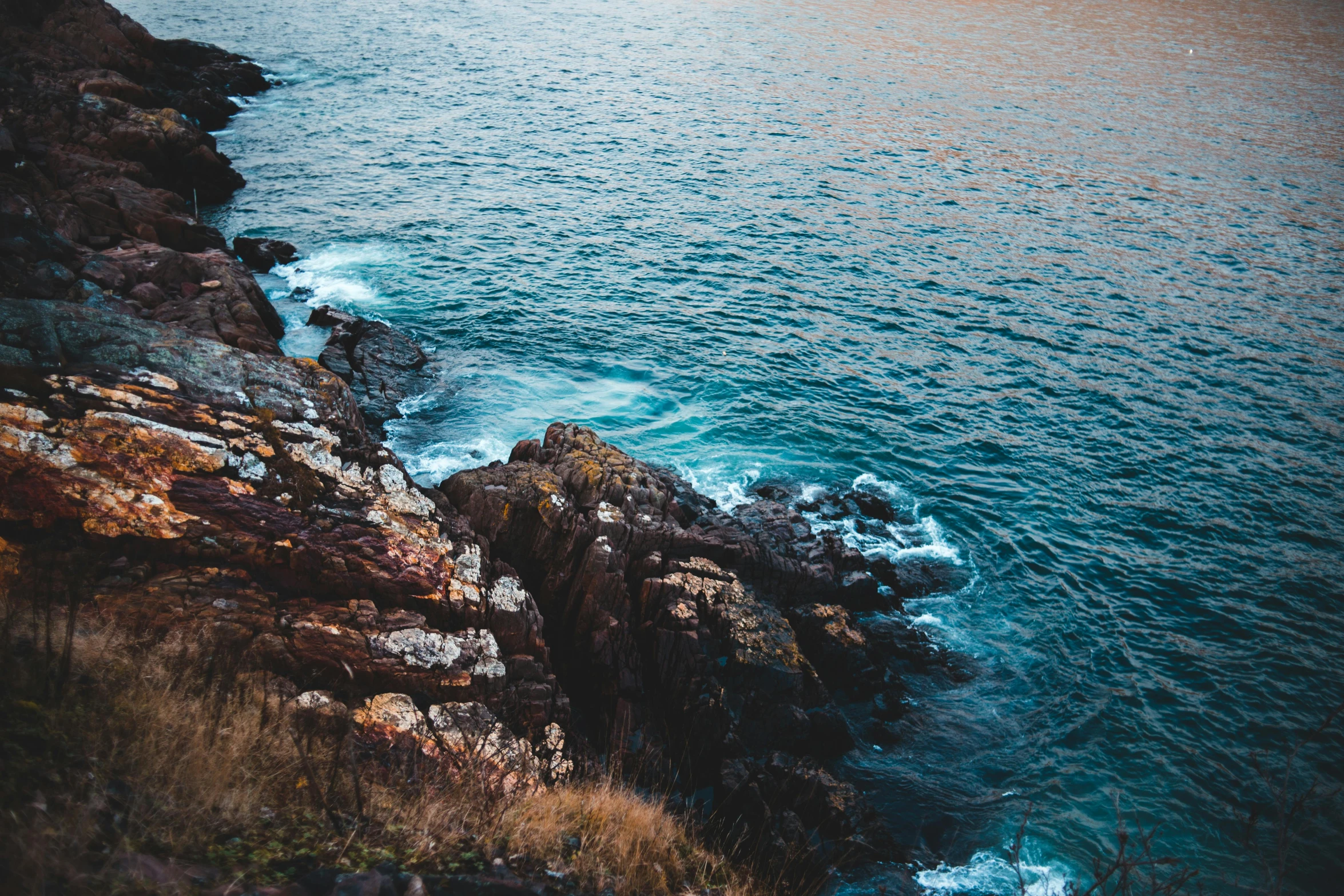 a large body of water next to a rocky shore, inspired by Elsa Bleda, pexels contest winner, happening, steep cliffs, manly, brown