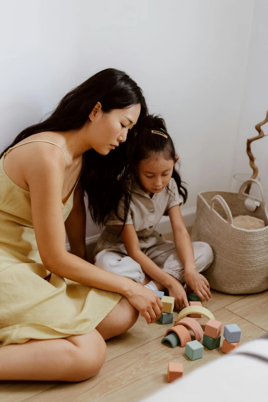 a woman and a child sitting on the floor playing with blocks, inspired by Ruth Jên, wearing wheat yellow gauze, manila, precious moments, brand