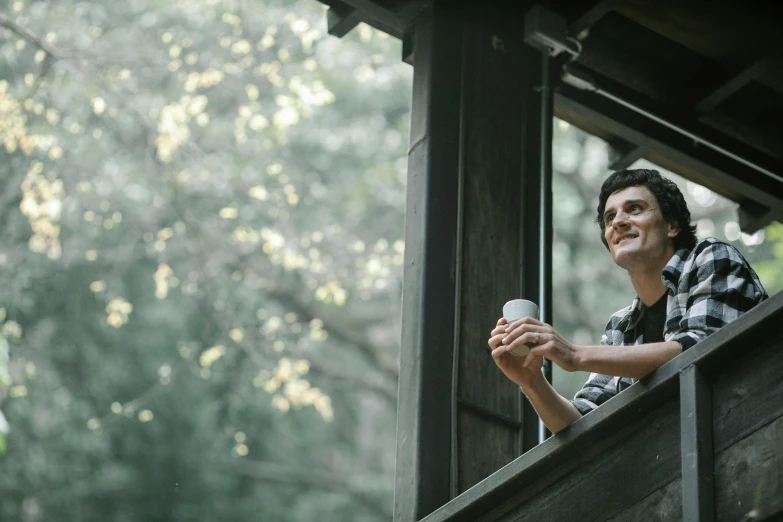 a man that is looking out of a window, beachwood treehouse, smiling man, drinking a cup of coffee, profile image