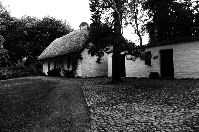 a black and white photo of a thatched house, by Kevin Connor, pexels contest winner, realism, cobblestone roads, alvar aalto, 1 9 7 0 s photo, scottish