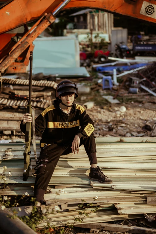 a man sitting on top of a pile of wood, inspired by Oka Yasutomo, unsplash, realism, photograph of a techwear woman, demolition, vietnam, black and yellow