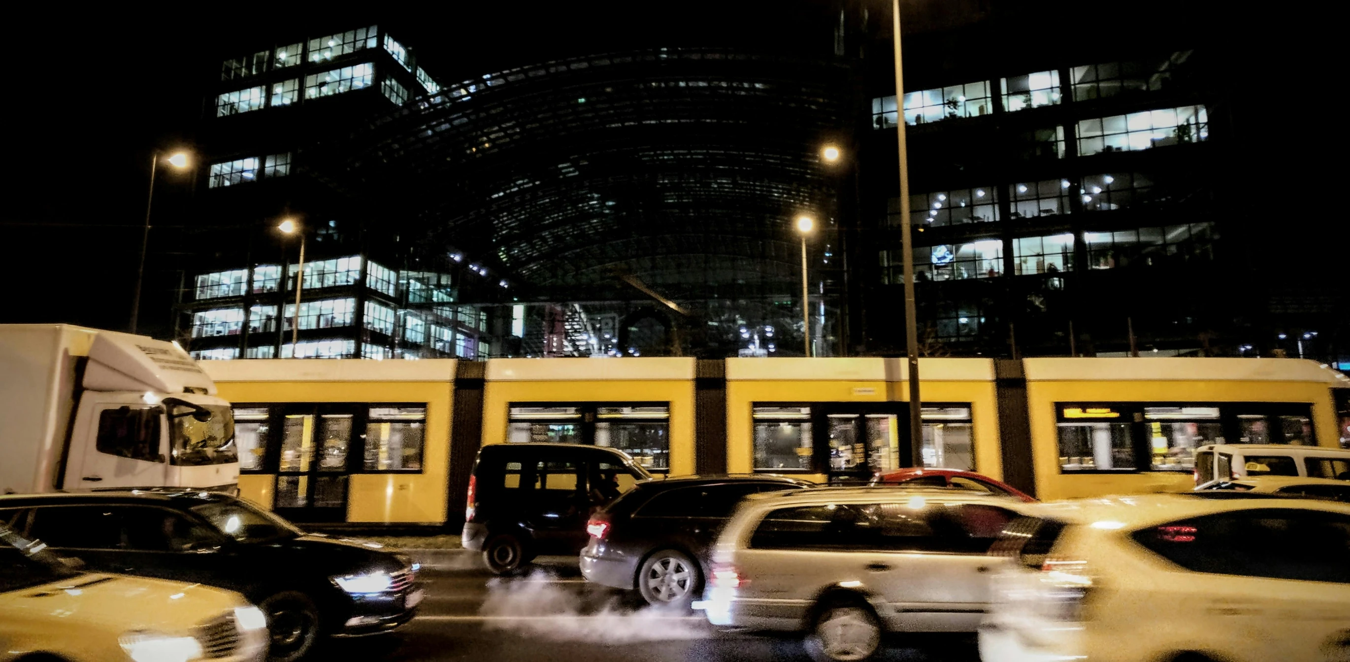 a street filled with lots of traffic next to tall buildings, a picture, by Thomas Häfner, night time footage, trains in the background, square, thumbnail