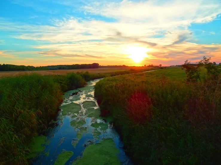 a river running through a lush green field, looking out at a sunset, prairie, slide show, gopro photo