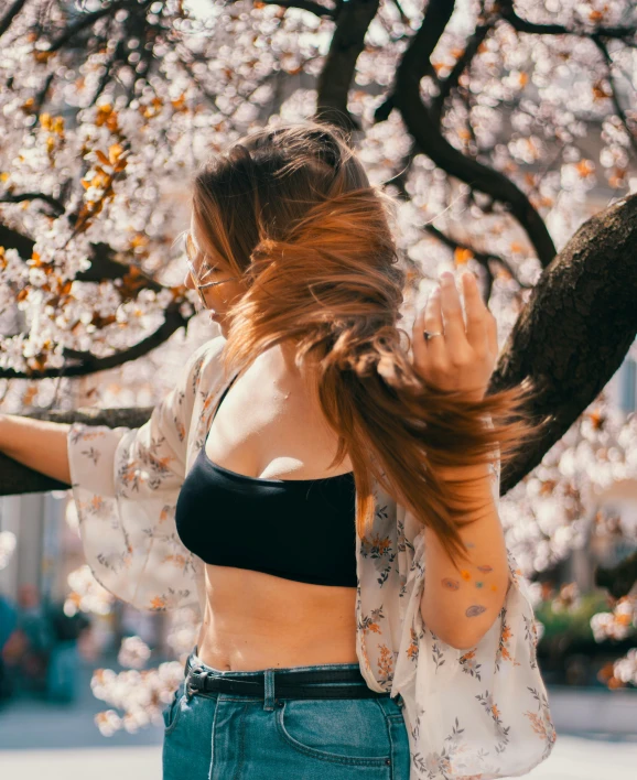 a woman with long hair standing in front of a tree, trending on pexels, happening, blossoming rhythm, wearing bra, spring season city, instagram post
