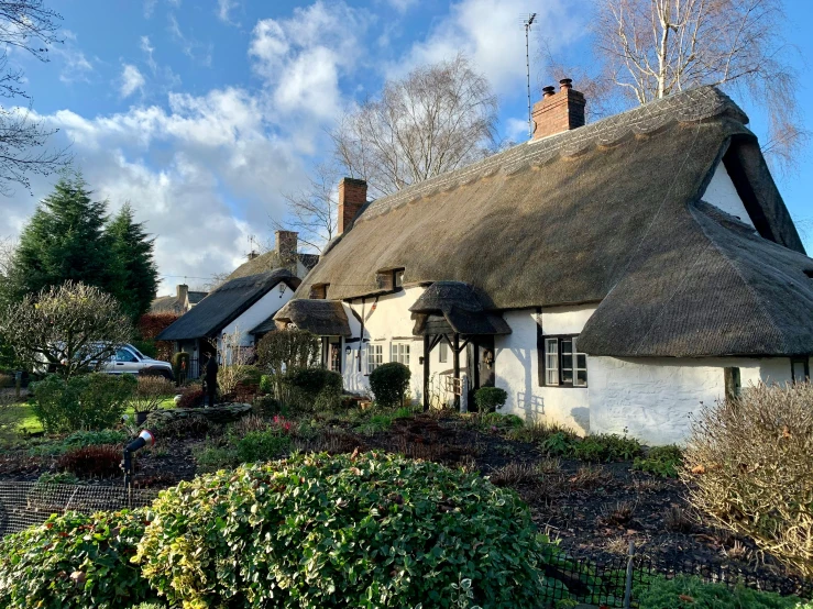 a white house with a thatched roof, by Kev Walker, pexels contest winner, taken on iphone 1 3 pro, several cottages, cozy, walton ford