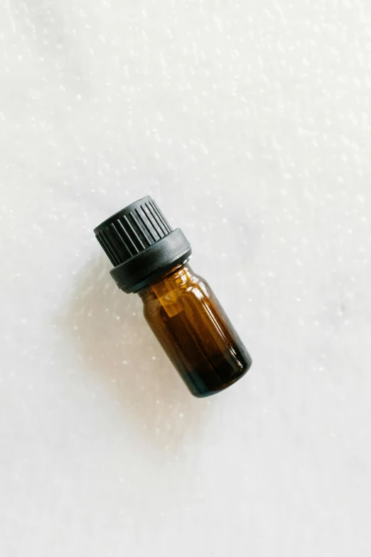 a bottle of essential oil on a white surface, by Carey Morris, unsplash, detailed product image, brown, overcast, vibrating