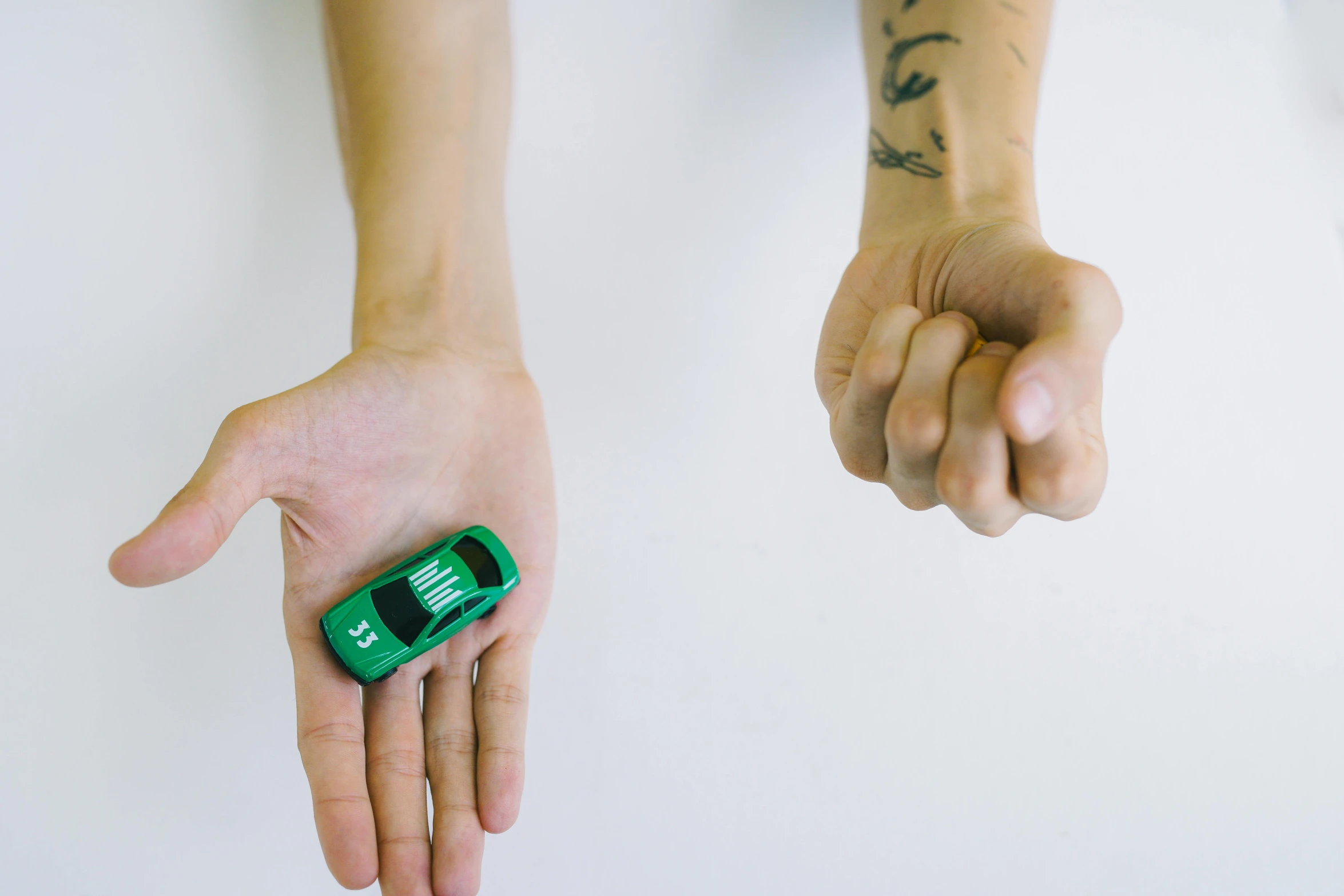 a person holding a green cell phone in their hand, a tattoo, by Adam Marczyński, unsplash, visual art, miniature of a sports car, size difference, stop motion animation, fight