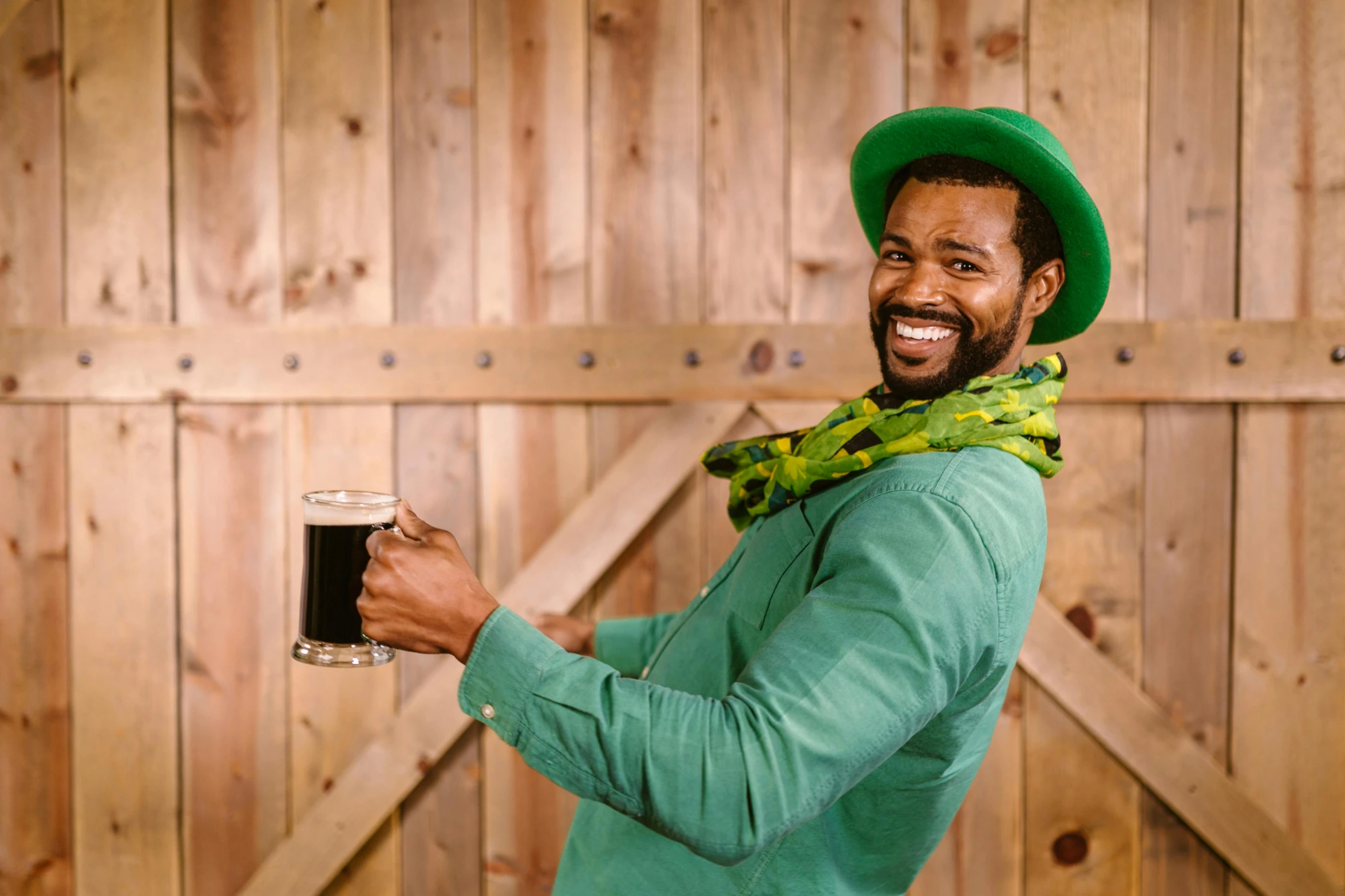 a man in a green shirt holding a glass of beer, pexels contest winner, renaissance, black curly beard, playful peasant man, green suit and bowtie, smiling man