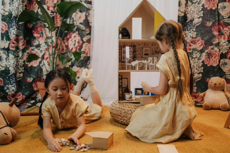 two little girls sitting on the floor playing with a doll house, pexels contest winner, conceptual art, gold clothes, sustainable materials, lady using yellow dress, joy ang