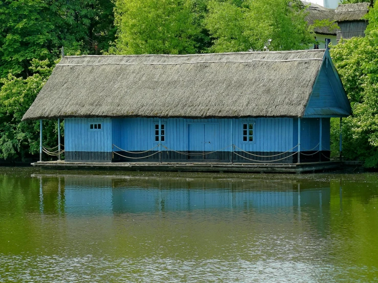 a blue house sitting on top of a lake, thatched roof, crystal palace, ewa juszkiewicz, museum photo