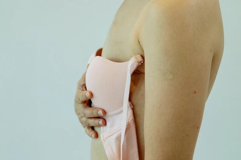 a close up of a person holding a pink object, wearing bra, bandage, over-the-shoulder shot, image