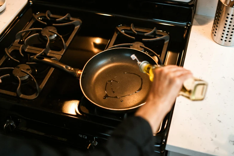 a person holding a frying pan over a stove, olive oil, thumbnail, full res, seattle