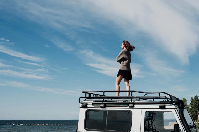 a woman standing on top of a white van, unsplash, land rover defender, seaview, thumbnail, clear skies