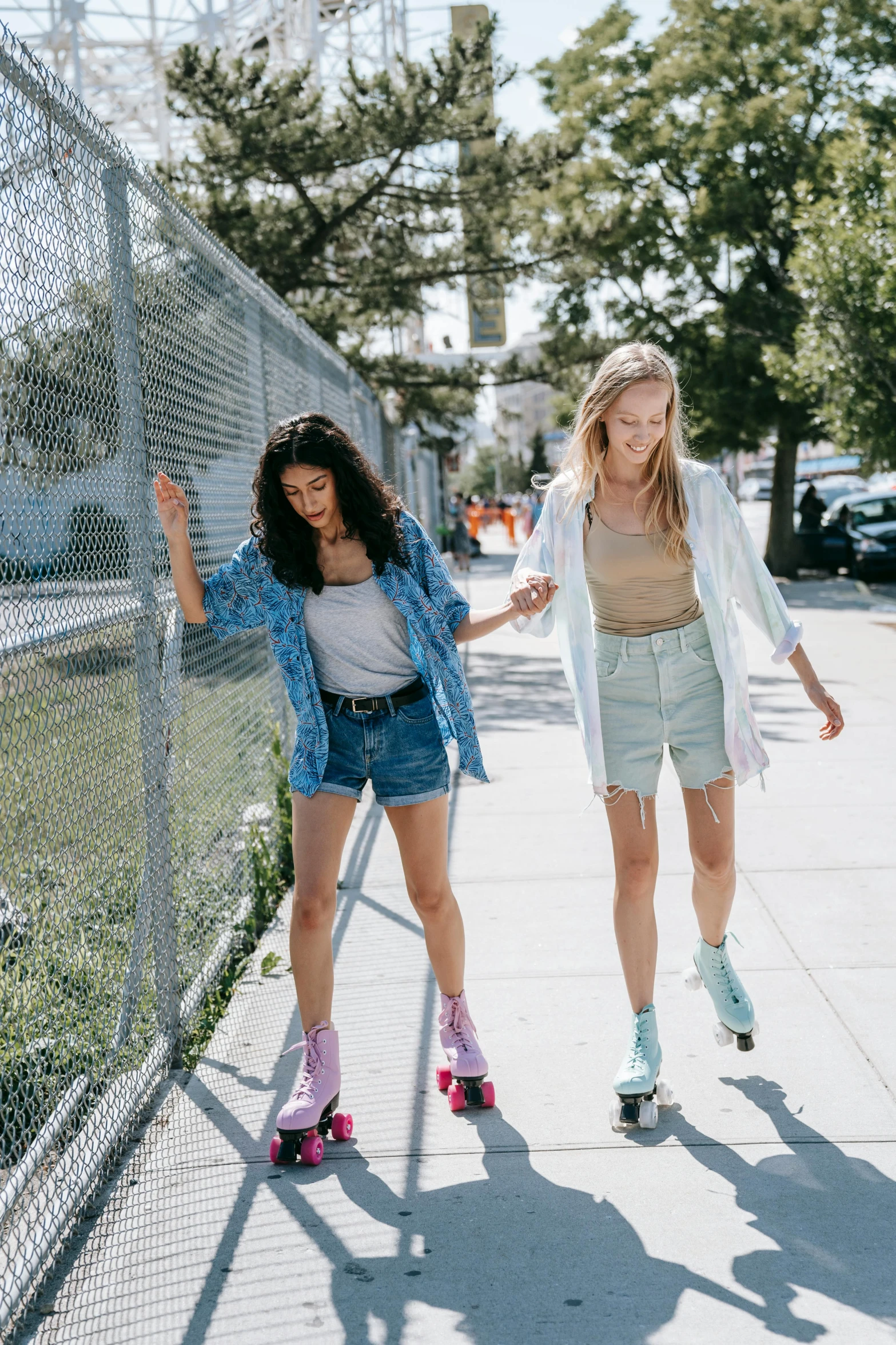 two women rollerblading down a sidewalk next to a fence, trending on unsplash, block party, lookbook, bright summer day, friends