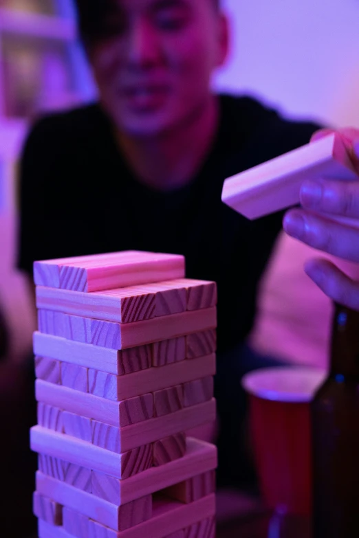 a man playing a game with a remote control, by Niko Henrichon, jenga tower, drinking at the bar, up-close, rave art
