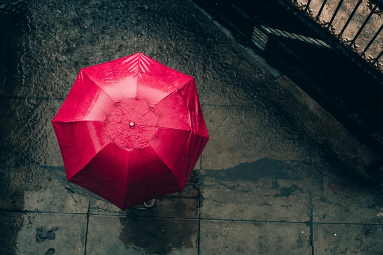 a red umbrella sitting on top of a sidewalk, unsplash contest winner, looking down from above, carnal ) wet, lgbtq, gif