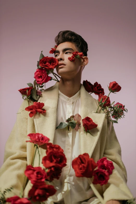 a man sitting in front of a bunch of red roses, an album cover, inspired by Russell Dongjun Lu, trending on pexels, romanticism, beautiful androgynous prince, asian man, floral couture, bella poarch