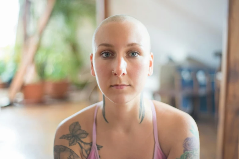 a woman with tattoos sitting in front of a mirror, a portrait, pexels contest winner, partially bald, padmasana, mid 2 0's female, headshot photo