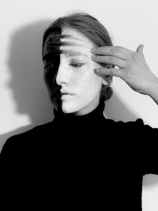 a black and white photo of a woman with white paint on her face, a black and white photo, inspired by Anna Füssli, left hand propping up the head, duality, mandy jurgens golden ratio, shadow effect