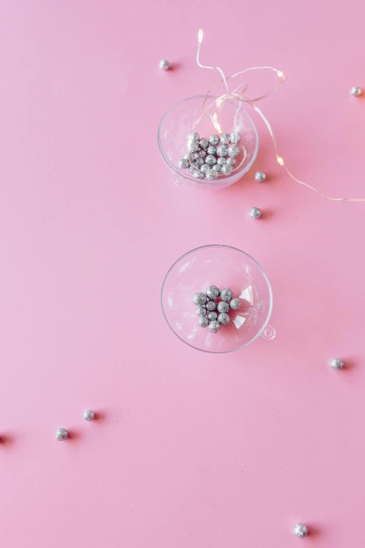 a couple of wine glasses sitting on top of a pink surface, beads, grey and silver, top - down photograph, decorations