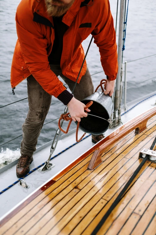 a man in an orange jacket on a boat, unsplash, watering can, sea cloud, oiled hardwood floors, grey