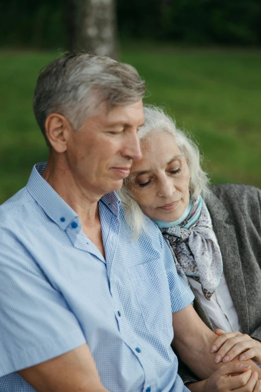 a man and a woman sitting on a bench, dark grey haired man, arm around her neck, profile image, grieving