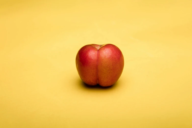 a red apple sitting on top of a yellow surface, by Jan Rustem, unsplash, hyperrealism, cervix awakening, judy chicago, arched back, peaches