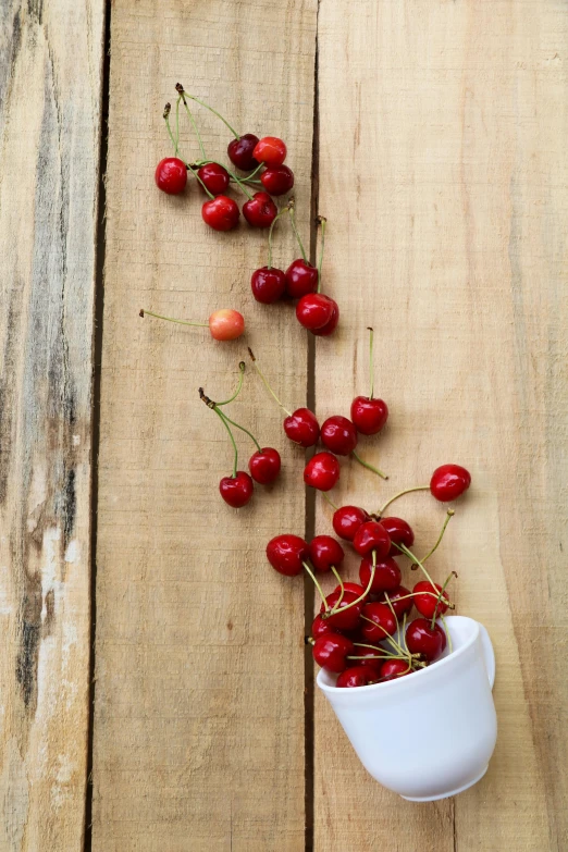 a white cup filled with cherries on top of a wooden table, profile image, chilean, vine, crisp image