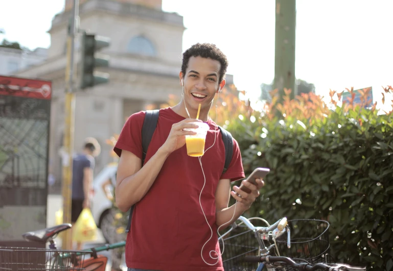 a man standing next to a bike with a drink in his hand, pexels, happening, drinking boba tea, earbuds, avatar image, male teenager