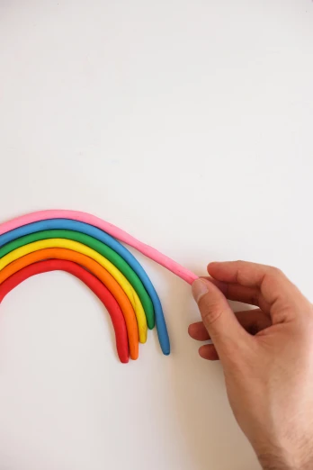 a person holding a pink toothbrush in front of a rainbow, by Rachel Reckitt, process art, 3 d clay sculpture, rubber hose style, with a white background, different sizes