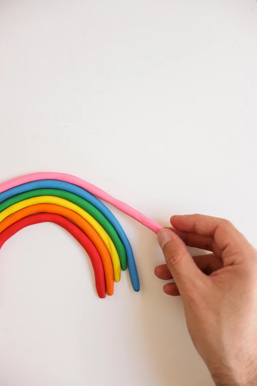 a person holding a pink toothbrush in front of a rainbow, by Rachel Reckitt, process art, 3 d clay sculpture, rubber hose style, with a white background, different sizes